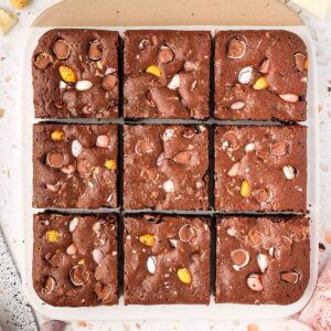 Easter brownies on a white and beige board seen from above, cut into 9 pieces.