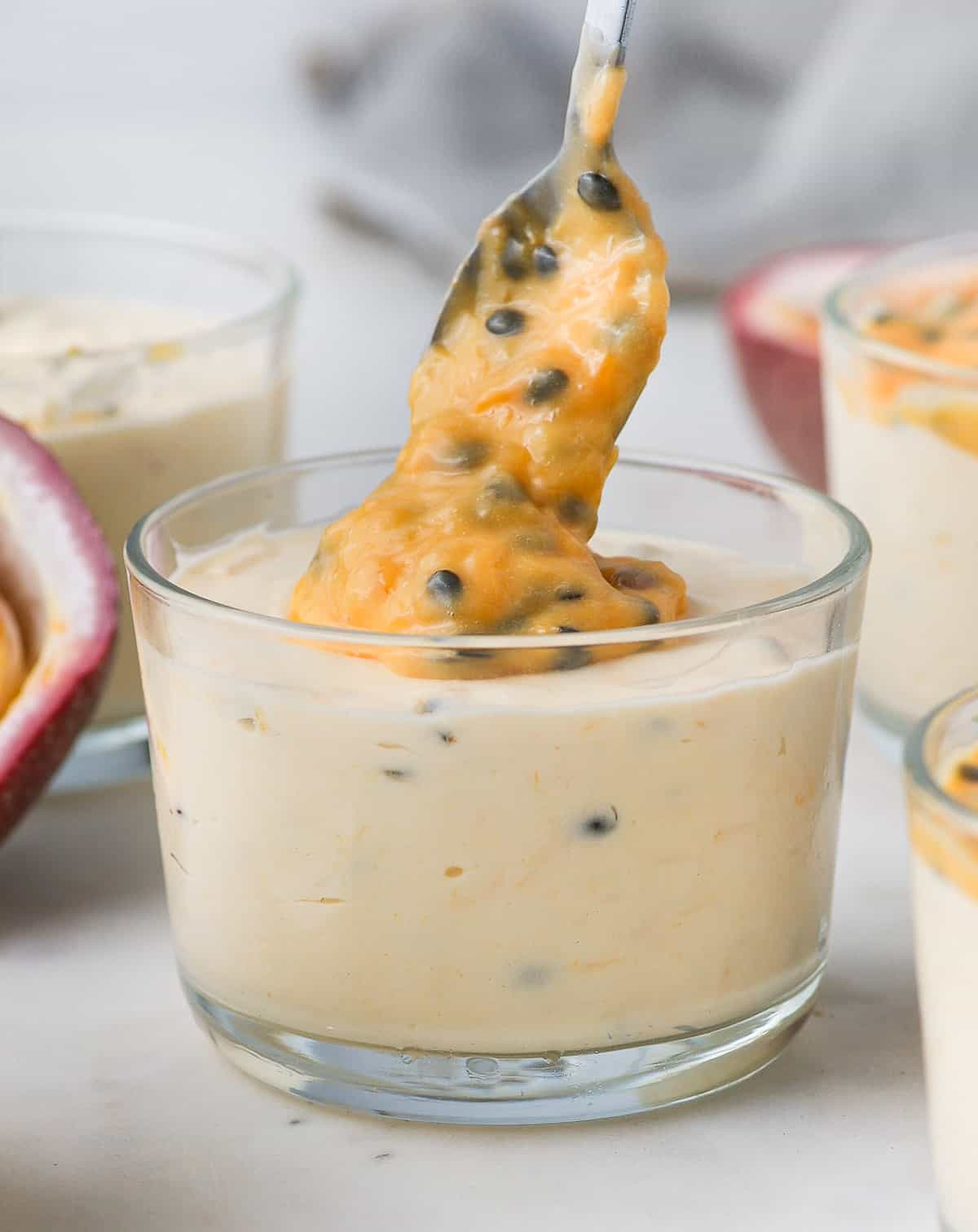 Pouring some curd over a passion fruit mousse cup.