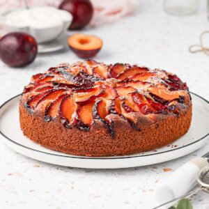 Plum Cake on a white plate topped with icing sugar.