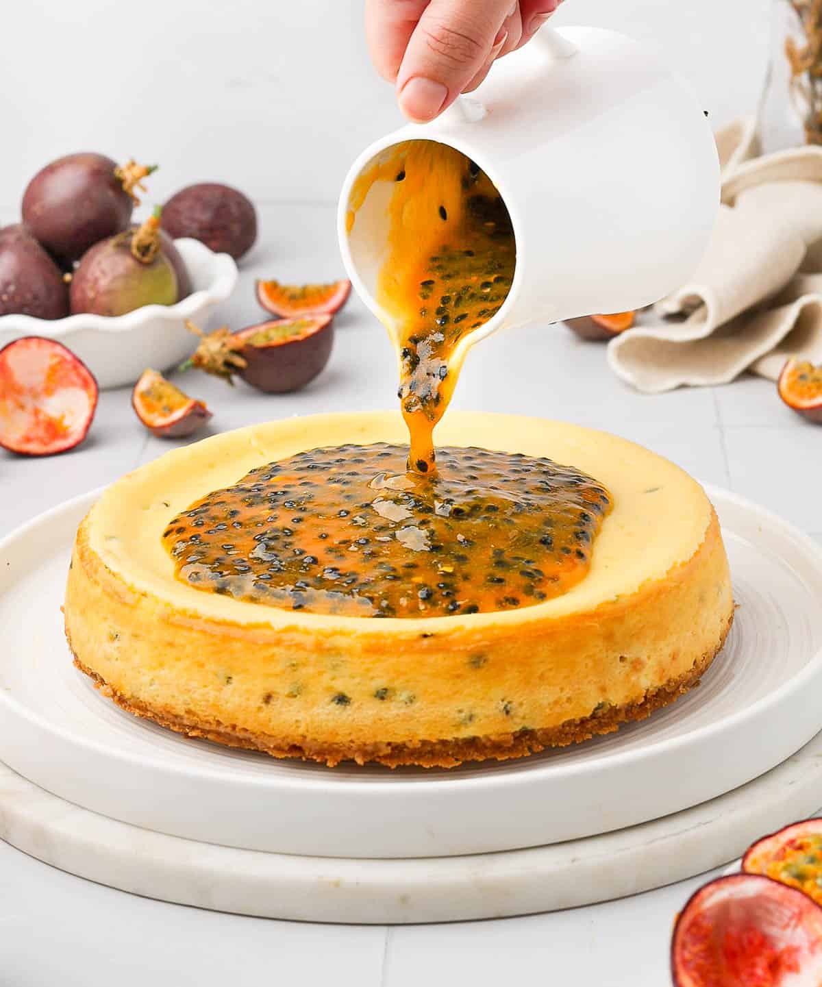 Pouring the passion fruit coulis topping over the cheesecake.