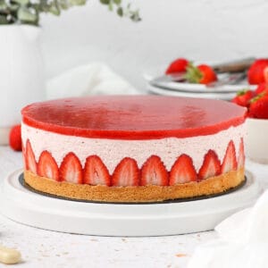 Cake on a white plate with a green plant in the background.