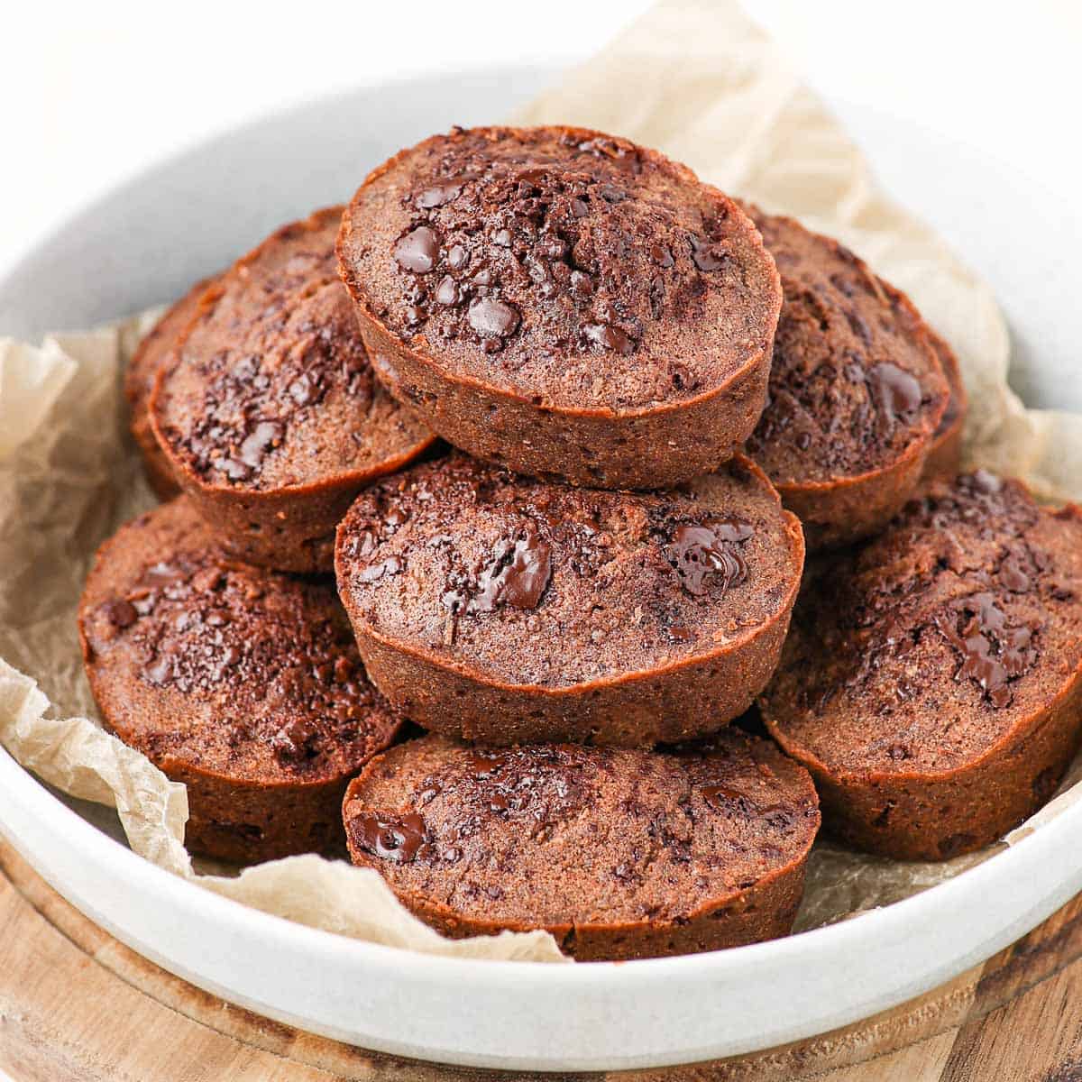 Close up on a stack of financiers cakes in a large white bowl.