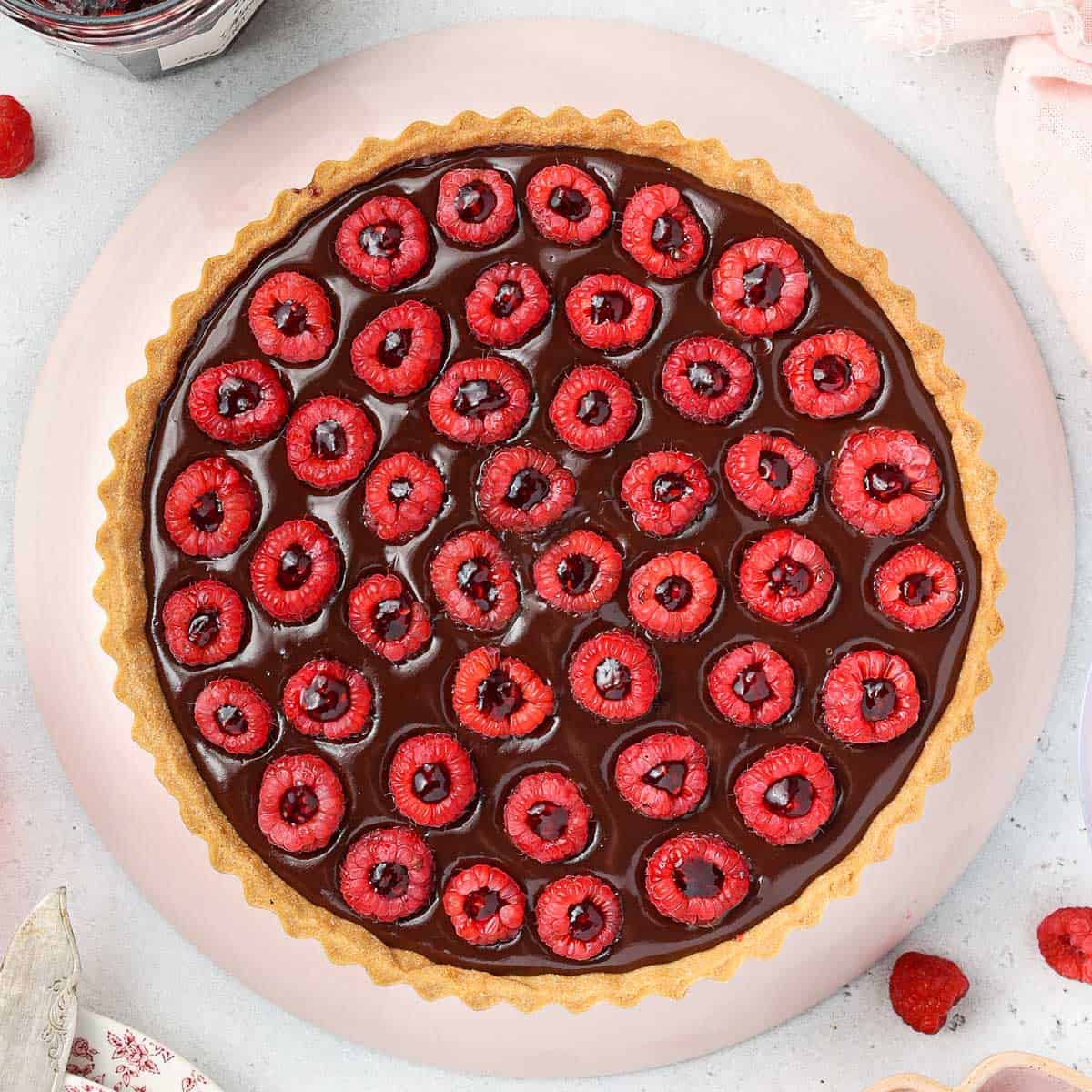 Chocolate tart seen from above over a pink plate.