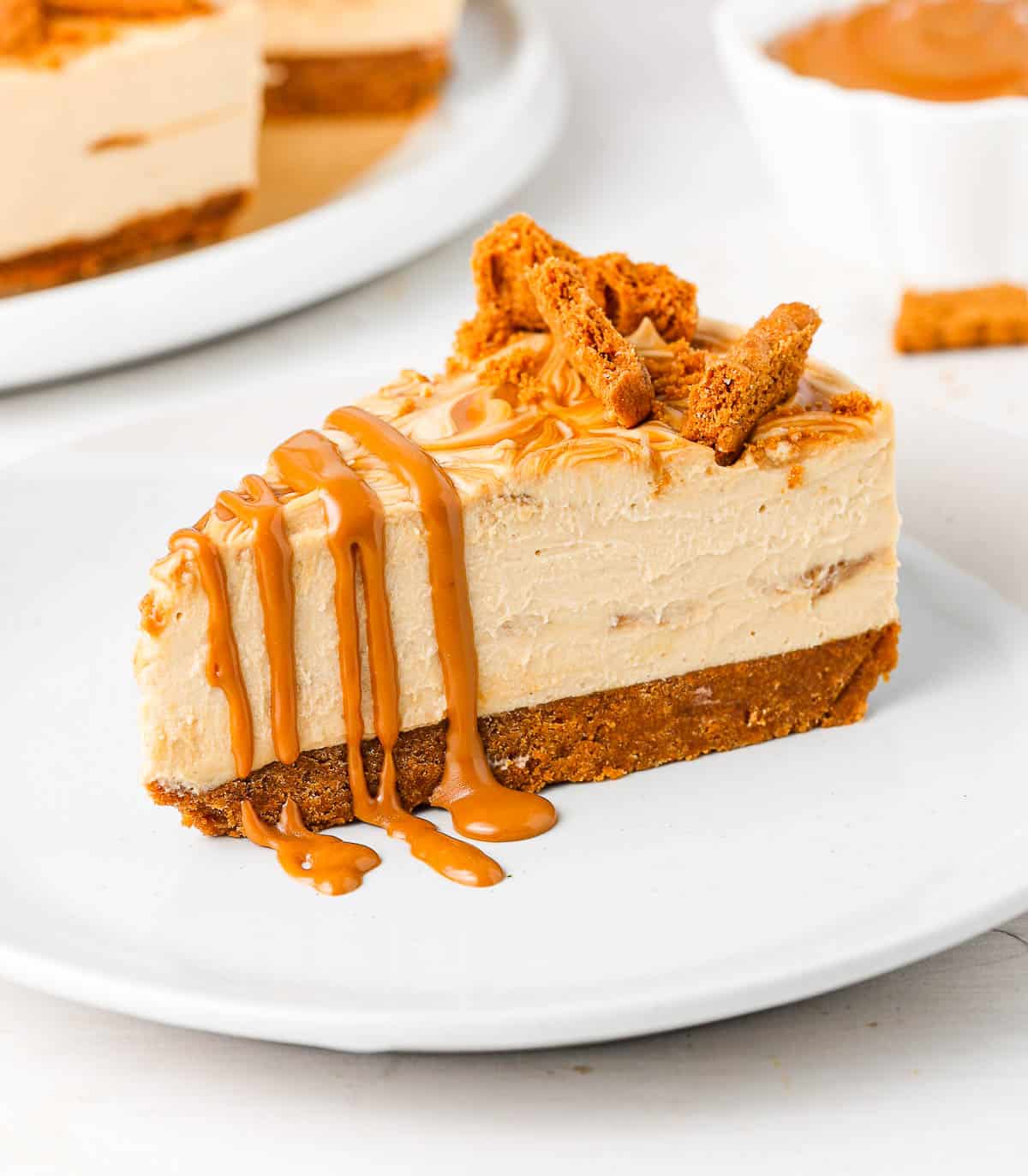 One slice of cake drizzled with biscoff on a small white plate.