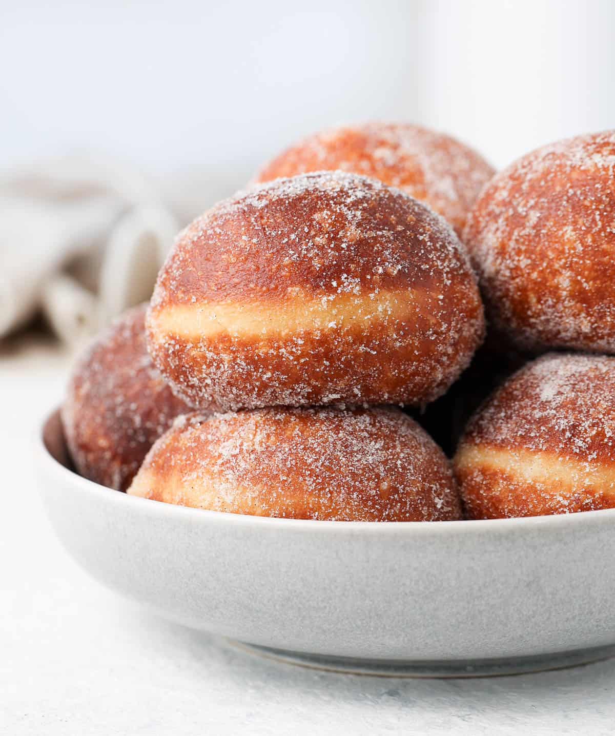 Close up on a stack of donuts inside a large grey serving bowl.