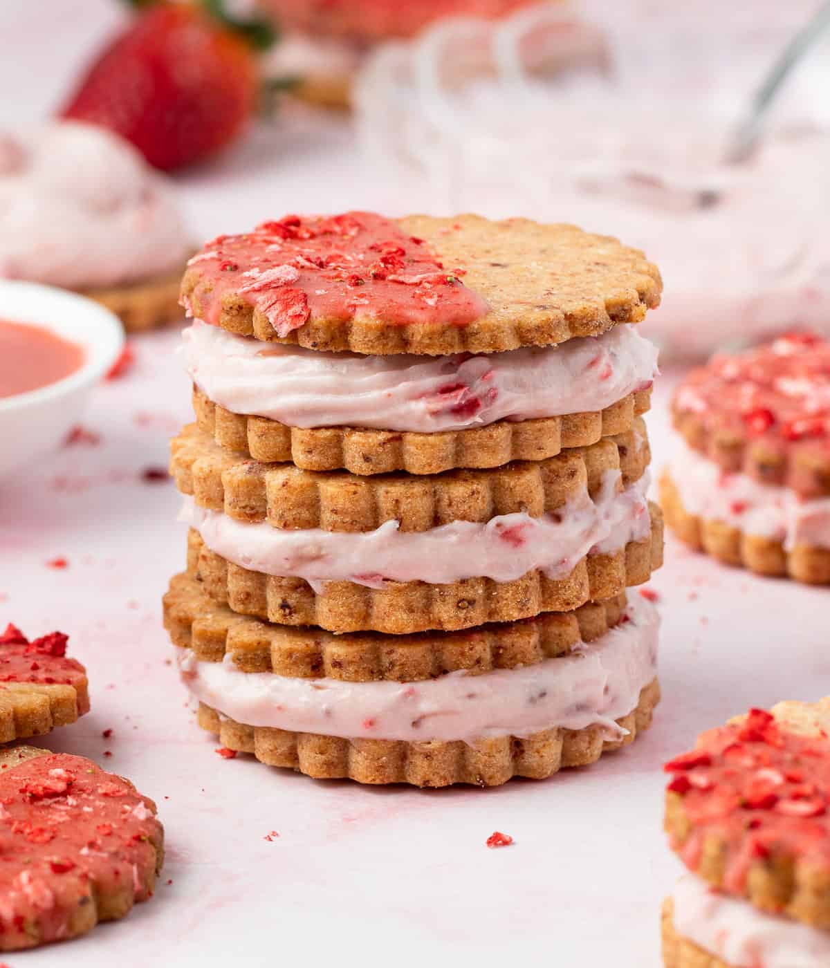 Three strawberry cookies stacked on top of each other over a pink surface.