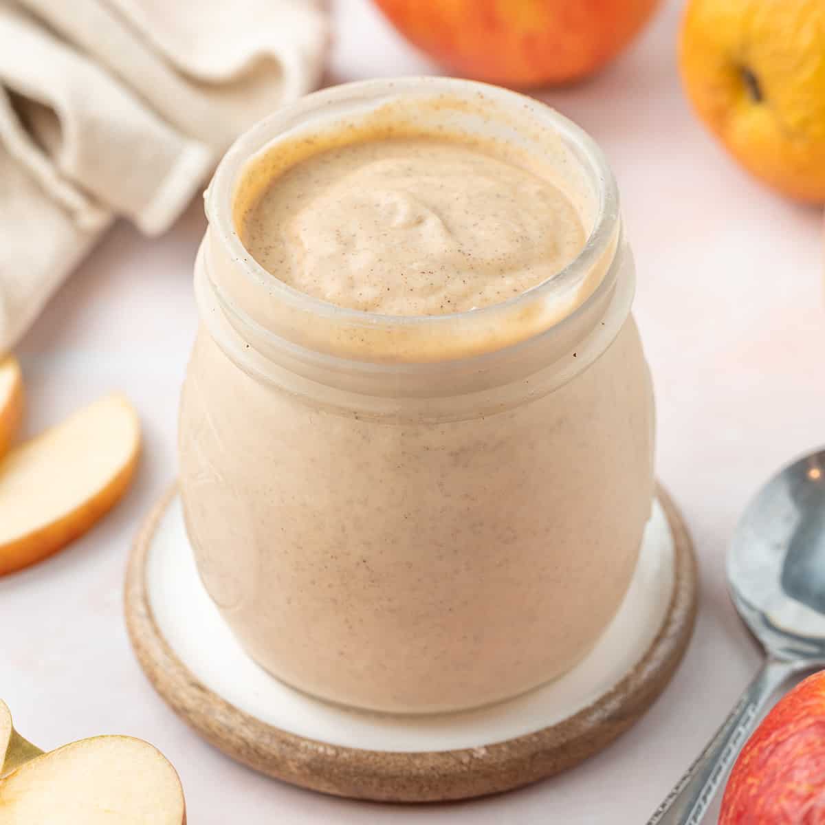 Curd in a preserve jar surrounded by apples and apple slices.