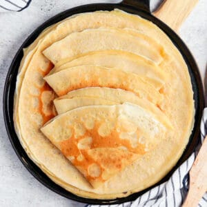Folded crepes over a black skillet seen from above.