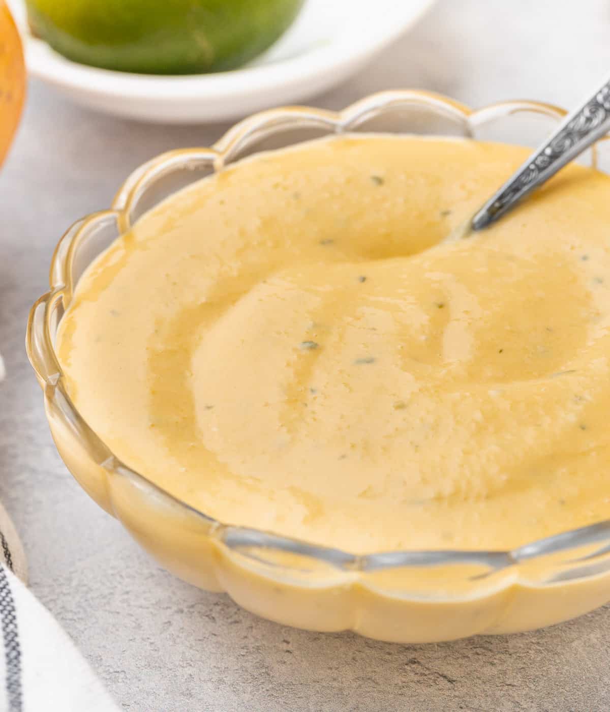 Curd in a glass bowl with a silver spoon dipped in.