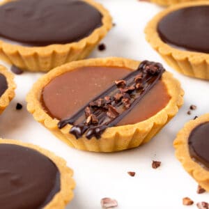 Close up on a caramel tart drizzles with chocolate.
