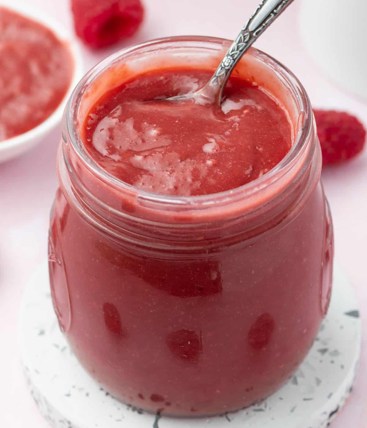 Close up on the curd placed inside a glass jar with a spoon.