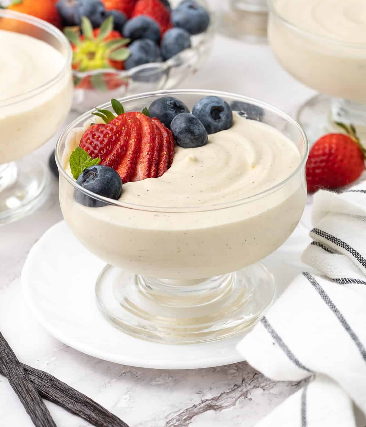 Mousse topped with fresh berries placed over a small white plate.