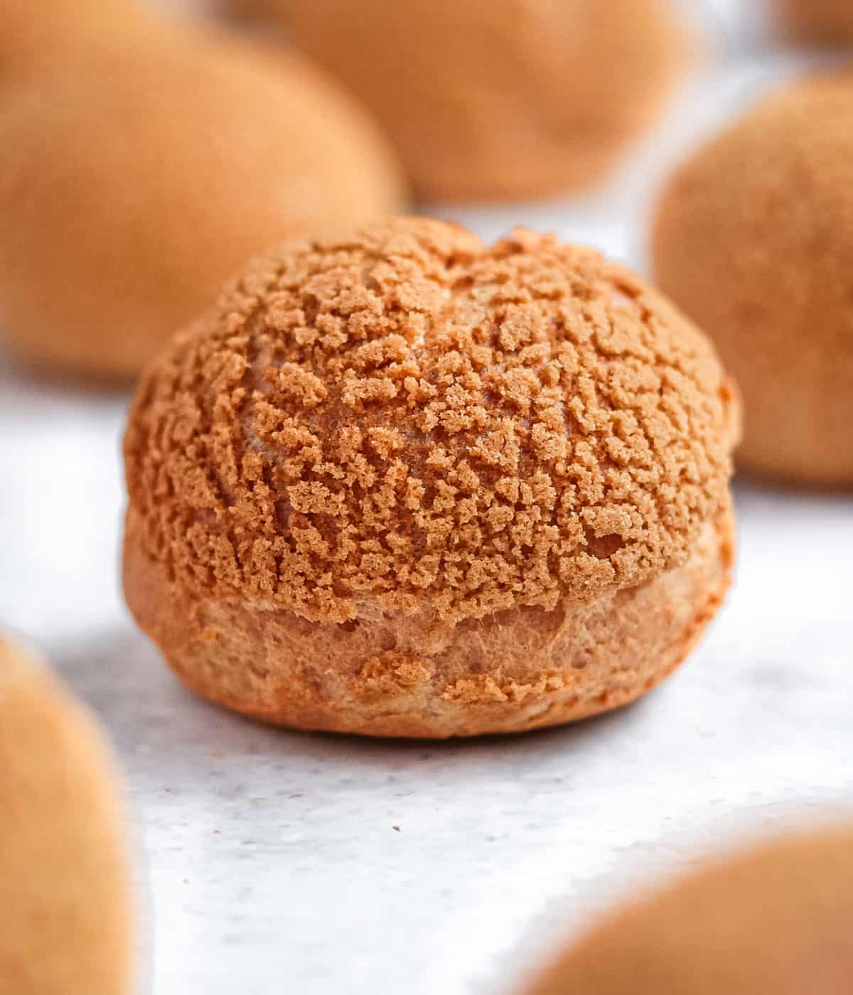 Plain choux, unfilled, over a light grey surface.