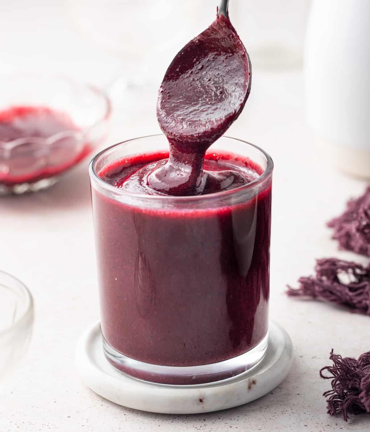 Coulis dripping from a spoon into a glass cup.