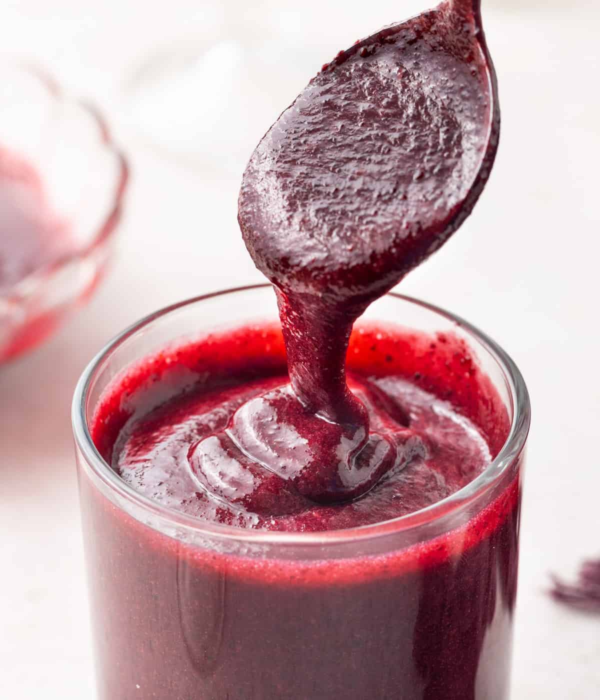 Close up on the coulis dripping from a spoon into a cup.