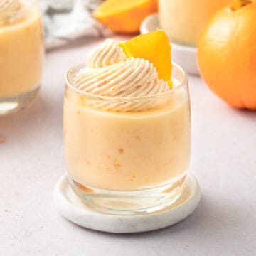 Mousse cup on a marble coaster over a light orange background.
