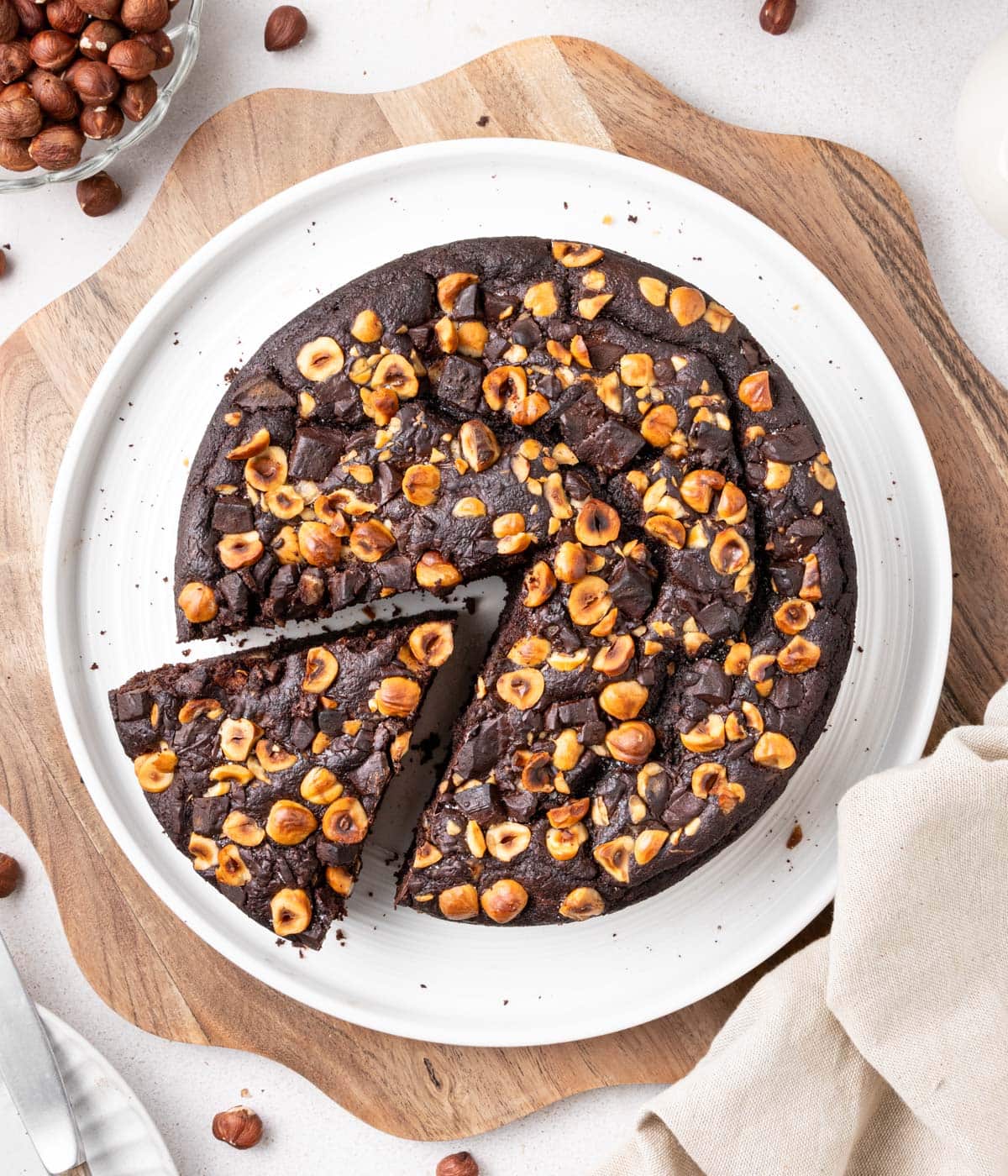 Cake on a white plate over wooden board seen from above, with a slice cut out.