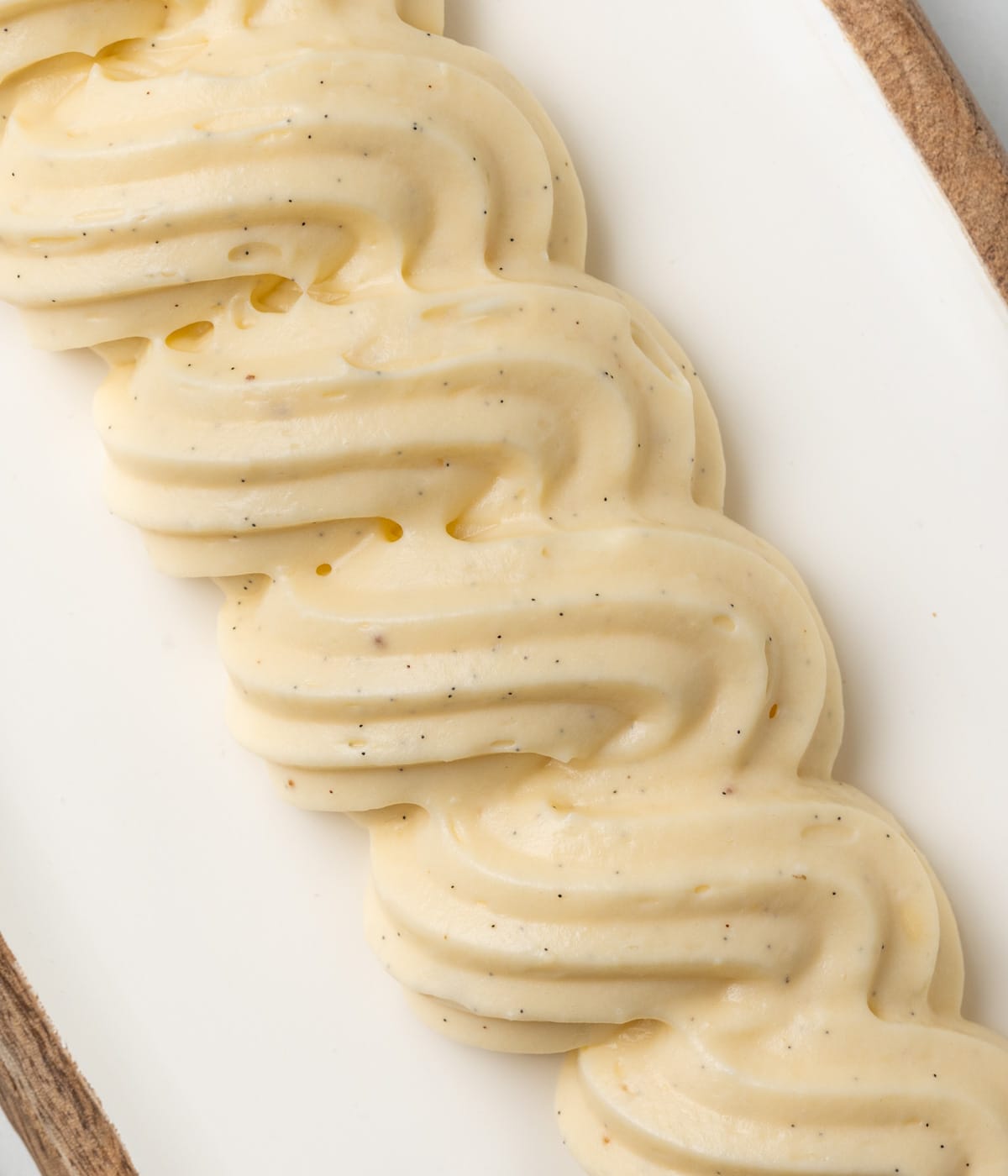 Swirls of cream in a line piped over a white tray - seen from above.