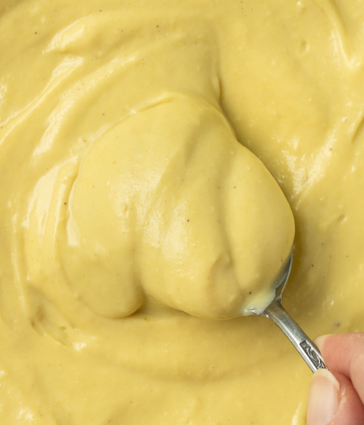 Close up on a spoon picking up pistachio cream seen from above.