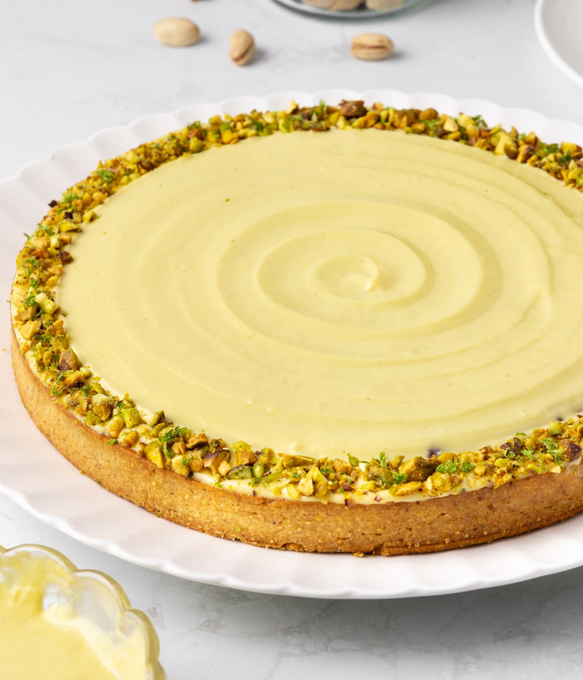 Close up on the side of the tart with the focus on the crust and crushed pistachio topping.