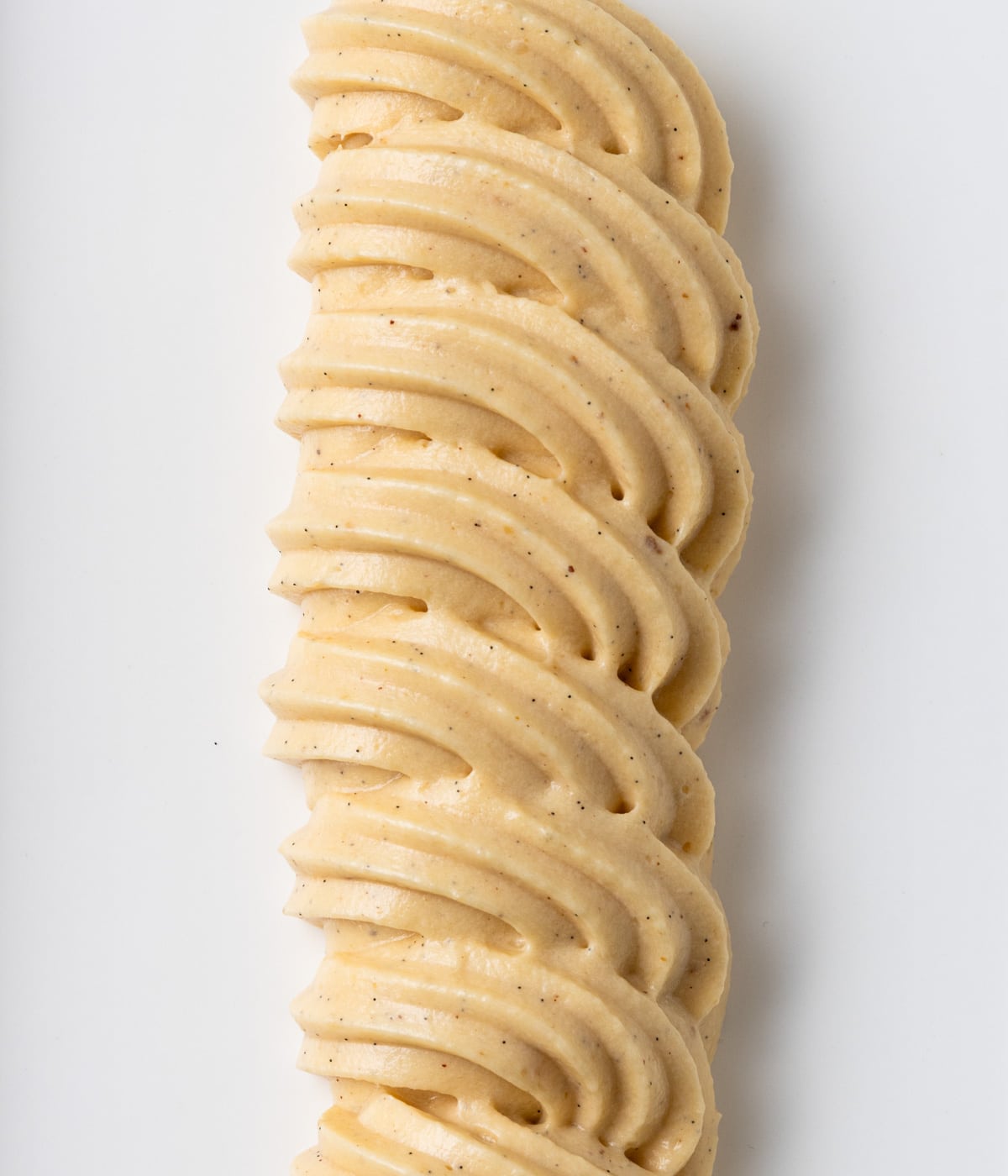 Line of praline cream swirls piped over a white plate, seen from above.