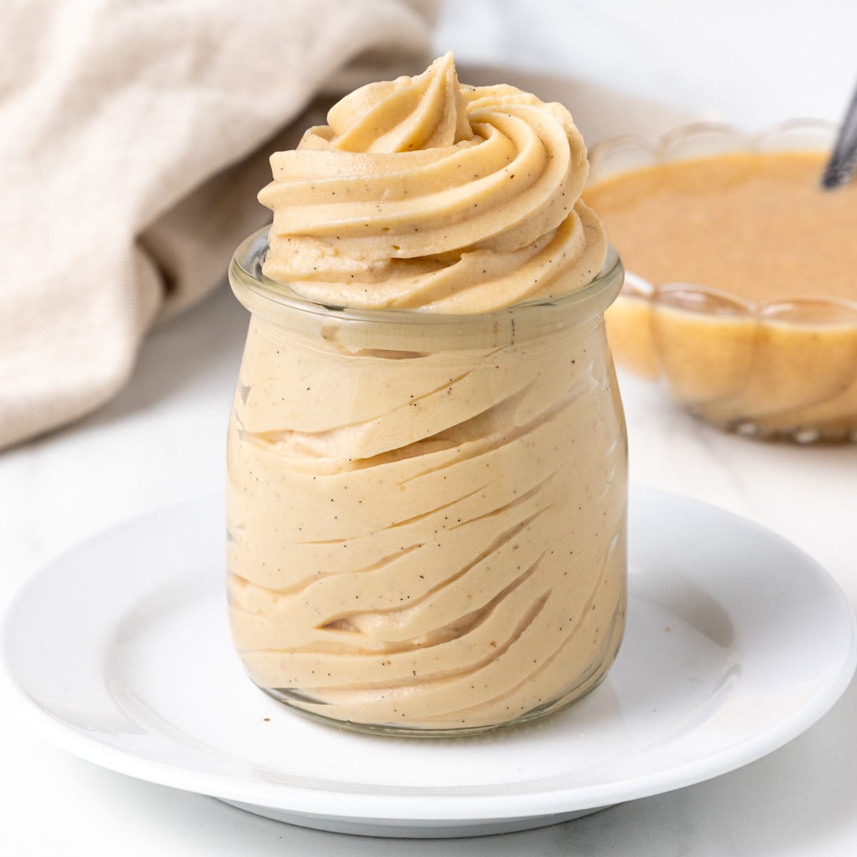 Swirls of praline mousseline cream piped inside a yogurt glass jar.