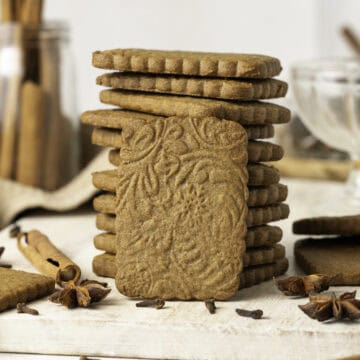 One speculoos cookie sitting upright against a stack of cookies.