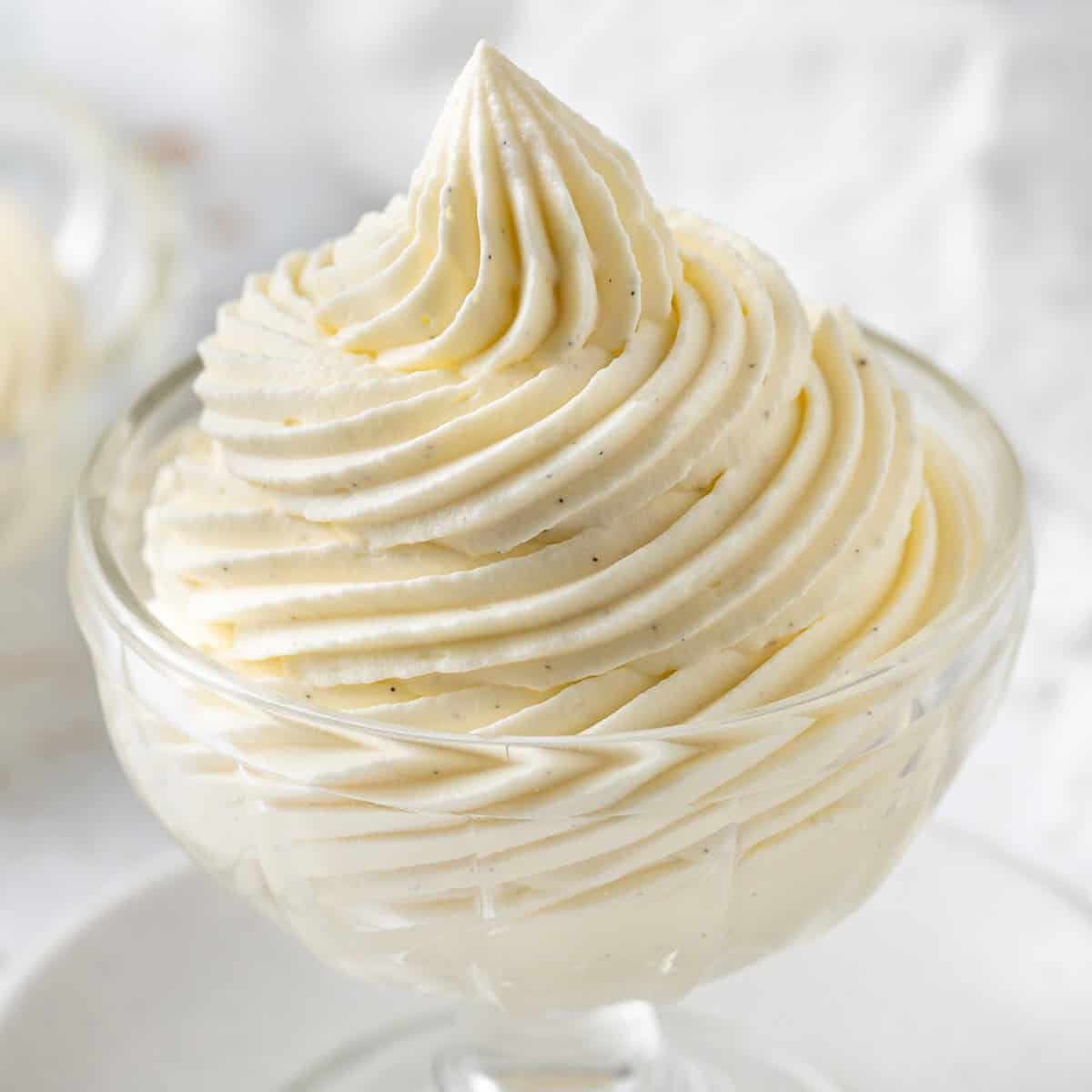 Close up on the cream piped in a swirl inside a glass dessert cup.