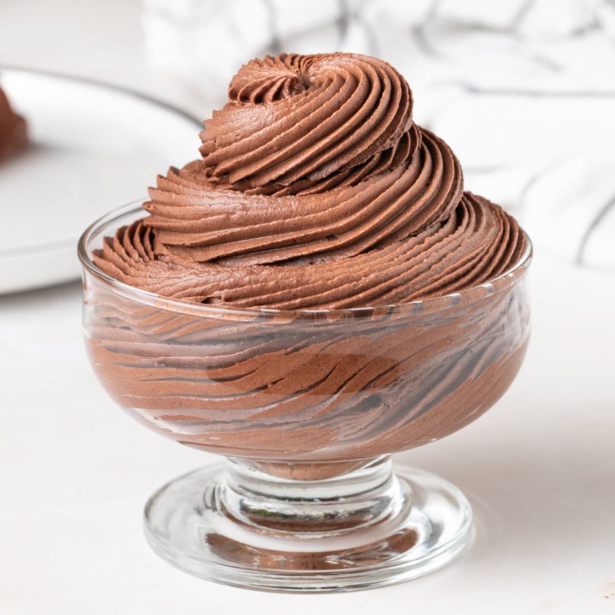 Chocolate whipped cream piped into a high swirl inside a glass dessert cup.