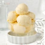 Ice Cream in a dessert cup inside a small white dish with striped napkin in the background.