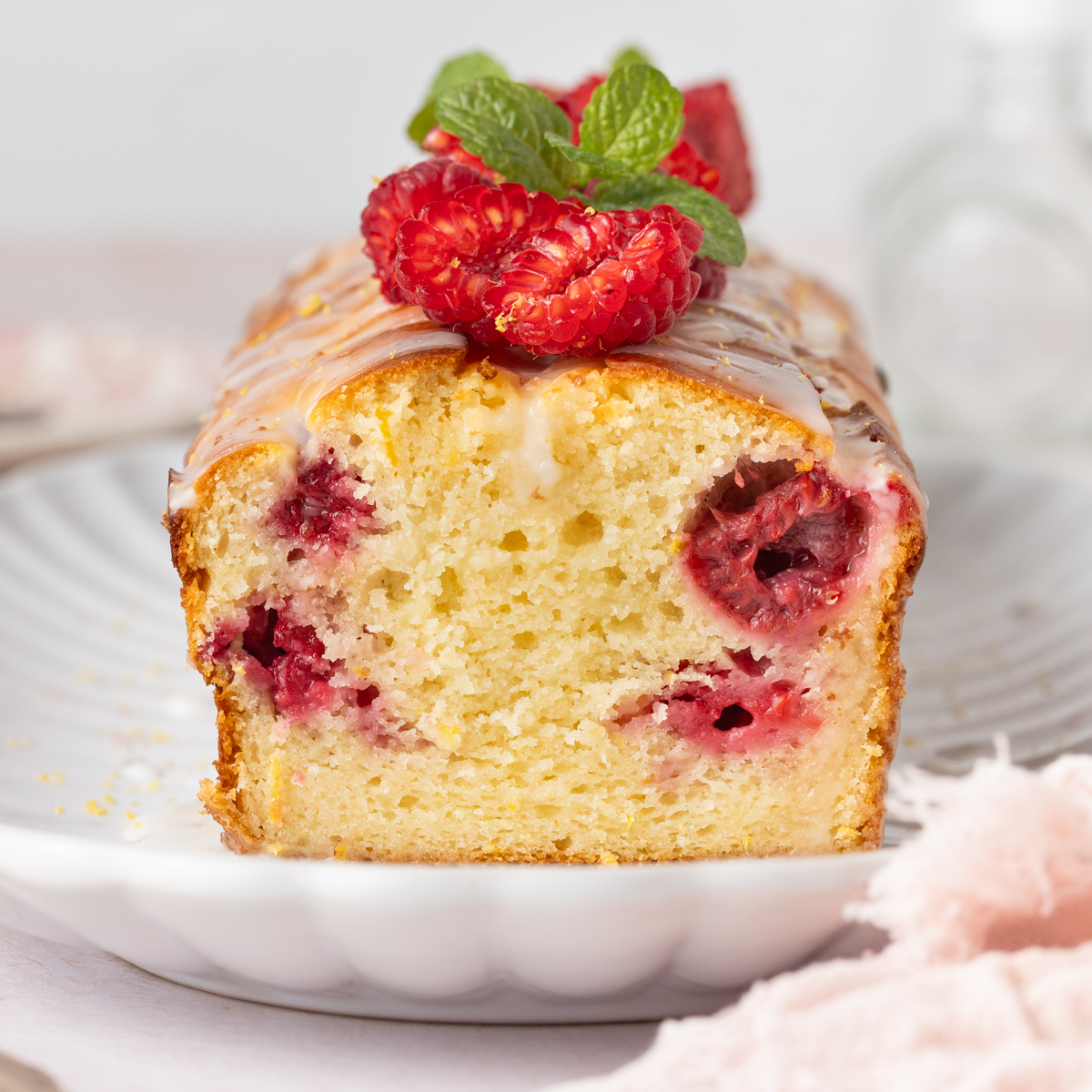 Close up on cake crumb showing the baked raspberries inside the lemon cake.