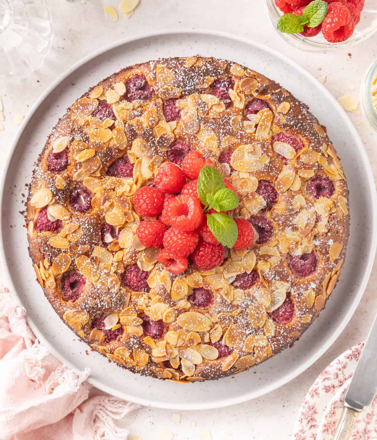 Cake topped with fresh raspberries and mint seen from above.